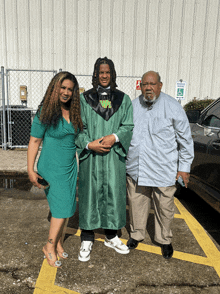 a man in a graduation cap and gown stands with his parents