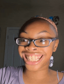 a girl wearing glasses and a headband making a funny face