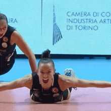 a woman laying on the floor with her arms outstretched in front of a screen that says camera di co industria arti di torino