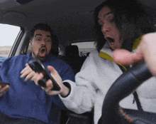 a man and a woman in a car with one holding a phone