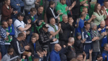 a crowd of people applauding in a stadium with a man wearing a black jacket with a canadian flag on it