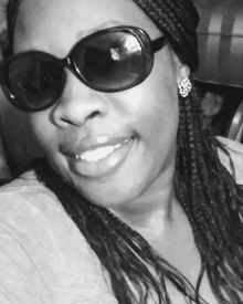 a woman wearing sunglasses and earrings smiles for the camera