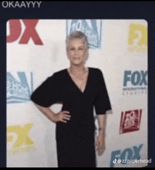 a woman in a black dress is standing in front of a fox advertisement