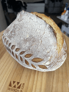 a loaf of bread sits on a wooden cutting board with winco written on it