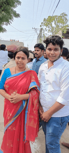 a woman in a red sari and a man in a white shirt stand next to each other