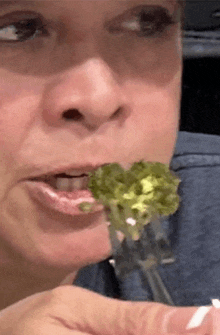 a woman is eating broccoli with a fork in her hand .