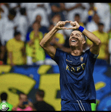 a soccer player wearing a blue kafd jersey makes a heart with his hands