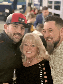 two men and a woman are posing for a picture with one man wearing a red hat that says " earl taylor "