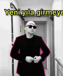 a man in a black suit and sunglasses is standing in a hallway with the words yeni yola girmeye written above him