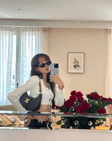 a woman taking a picture of herself in a mirror with roses in the background