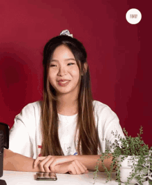 a woman sitting at a table with a plant in front of her and a red background with the word fever on it