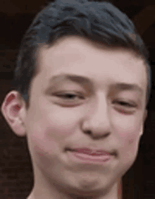 a close up of a young man 's face with his eyes closed and a smile on his face .