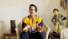 a man in a yellow jersey is sitting in a chair with his arms outstretched .