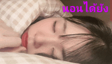 a girl is sleeping with her eyes closed and the words " นอน ได้ ยัง " written in pink