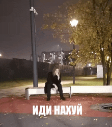 a woman sits on a bench in a park with the words " иди-нахуй " above her