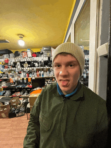 a young man wearing a beanie sticks his tongue out in a store