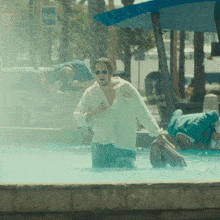 a man in a white shirt is standing in a pool of water with a sign that says taxis in the background