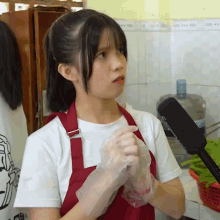 a girl wearing a red apron and white gloves stands in front of a microphone which says cnn on it