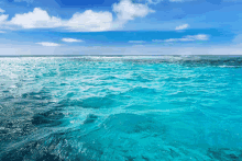 a large body of water with a blue sky and clouds in the background