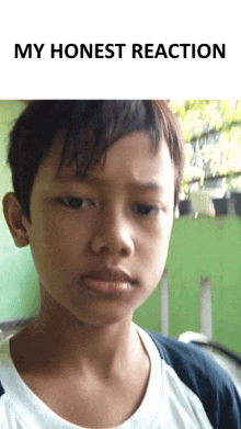 a young boy is making a funny face with the words `` my honest reaction '' written above him .