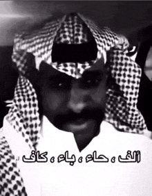 a black and white photo of a man wearing a head scarf with arabic writing on it