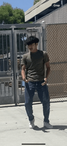 a man standing in front of a fence with a crop button on the bottom right