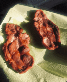 two pieces of meat sitting on a napkin on a table