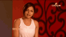 a woman in a white tank top stands in front of a red wall with the words semi final on the bottom