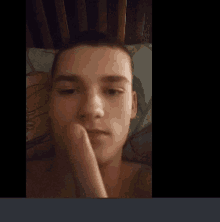 a young man laying on a bed with his hand on his face