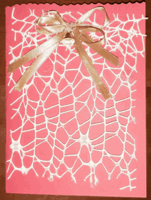 a pink card with a white lace pattern and a bell on it