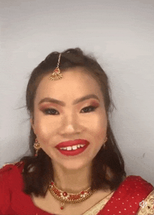 a woman in a red and gold dress with red lipstick is smiling .