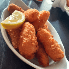 a bowl of fried food with a slice of lemon on the side