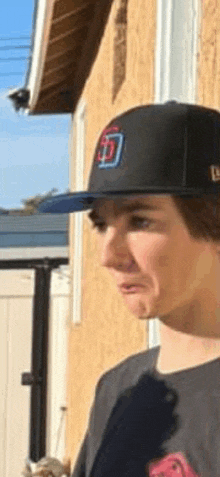 a man wearing a hat with the letter t on it is standing in front of a building .