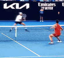 a man in a red shirt is playing tennis on a court with an emirates sky better banner behind him