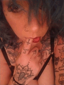 a woman with blue hair has a tattoo on her finger that says t.