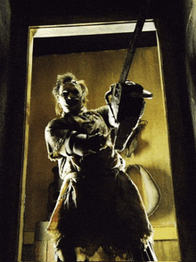 a man holding a chainsaw in a dark room