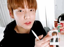 a young man holding a pen and a picture of himself with the big hit logo in the corner