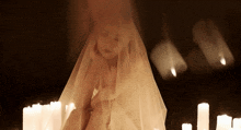 a woman with a veil on her head is surrounded by candles