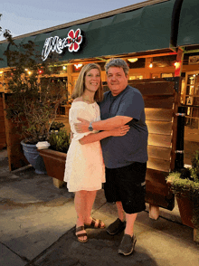 a man and woman are posing for a picture in front of a restaurant named merry 's