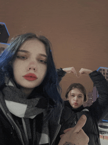 a girl with blue hair is making a heart with her hands