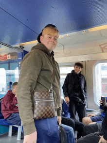 a man with a louis vuitton bag on his waist stands on a train