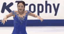 a woman in a blue dress is skating on a ice rink in front of a sign that says trophy .