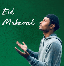 a man is praying in front of a green background that says ' eid mubarak ' on it