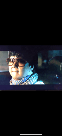 a woman wearing sunglasses and a scarf is driving a car