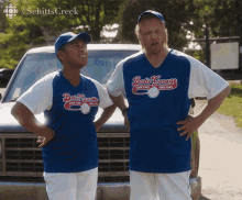 a man and a woman are standing in front of a truck wearing baseball jerseys that say bob 's garage