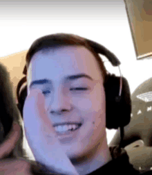 a young man wearing headphones is smiling and making a face