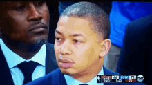 a man in a suit and tie is watching a basketball game between the cleveland cavaliers and the denver nuggets