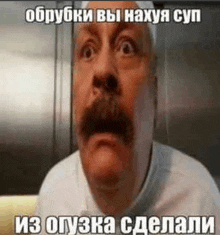 a man with a mustache is making a funny face with a meme in russian .