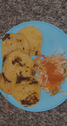 a blue plate with a few pieces of food and coleslaw