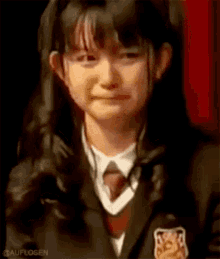 a young girl in a school uniform is crying while wearing a tie .